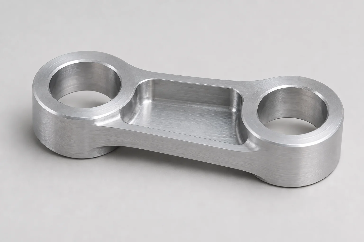 Machined robot-arm link with two bores and a rounded weight-relief pocket